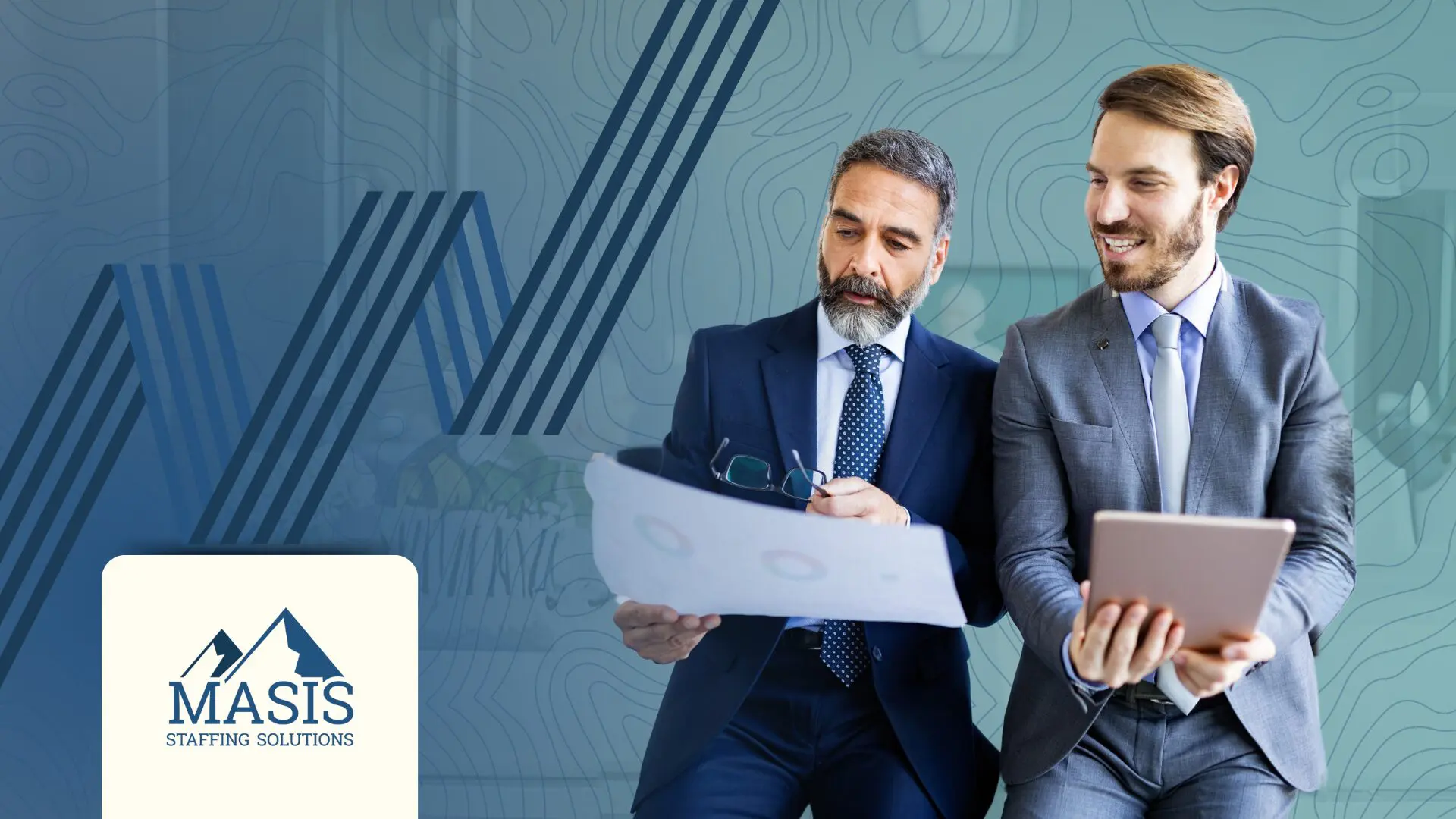 An older man holding a sheet of graphs speaks to a younger man holding a tablet