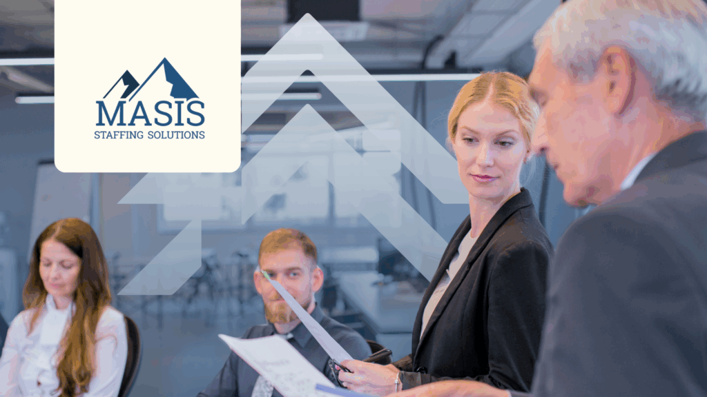 Employees in corporate attire sit or stand discussing around a conference table