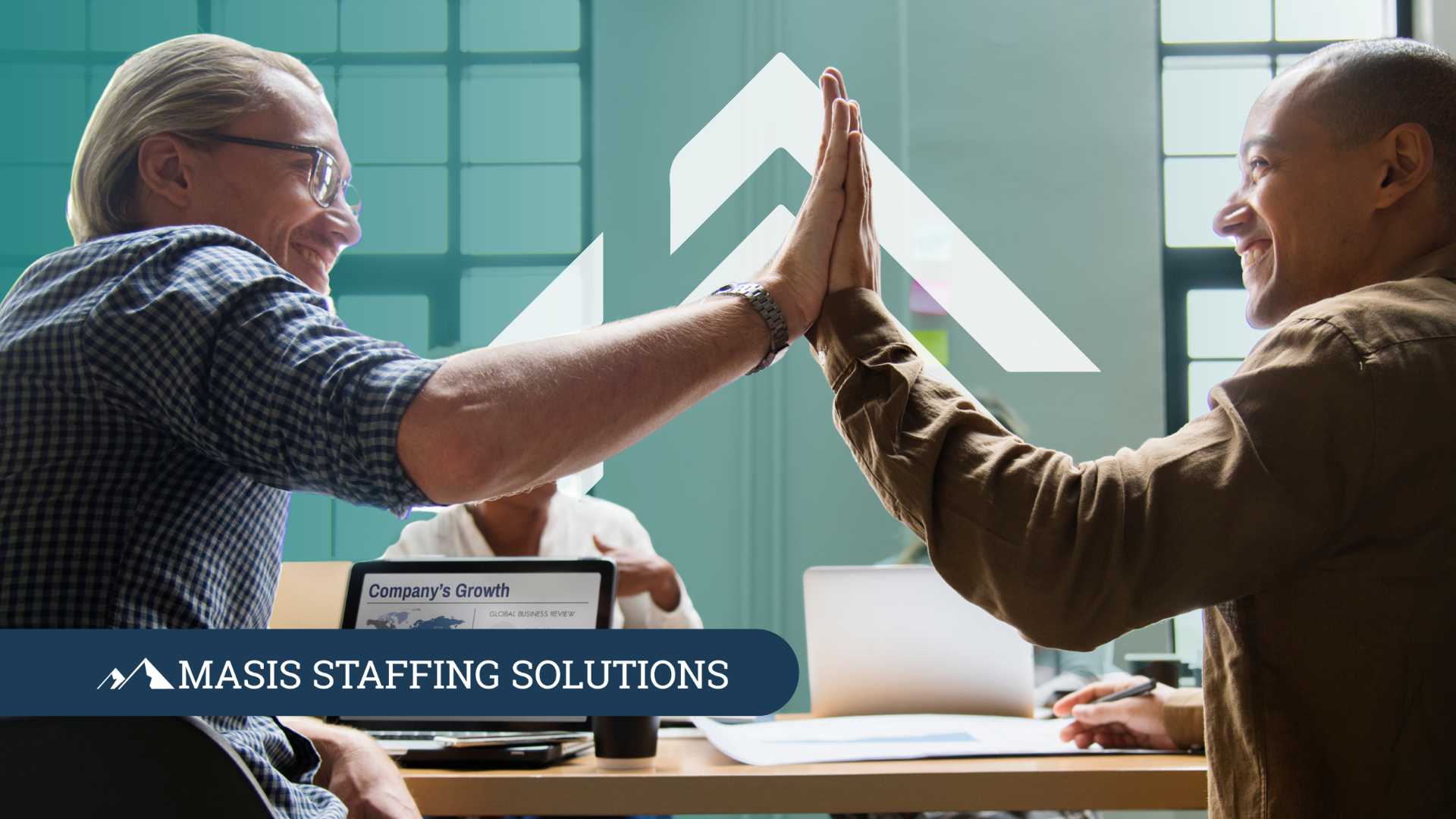 Two employees working together at a conference table give each other a high five