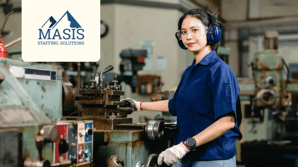 Manufacturing employee wearing safety hearing equipment operates machinery