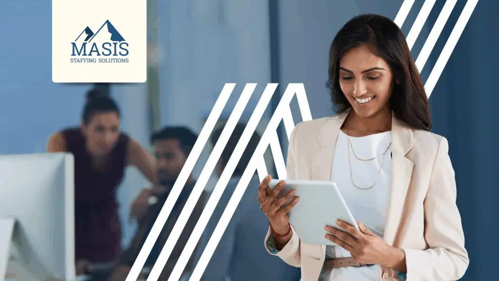 Admin staff stands holding a mobile tablet in the office