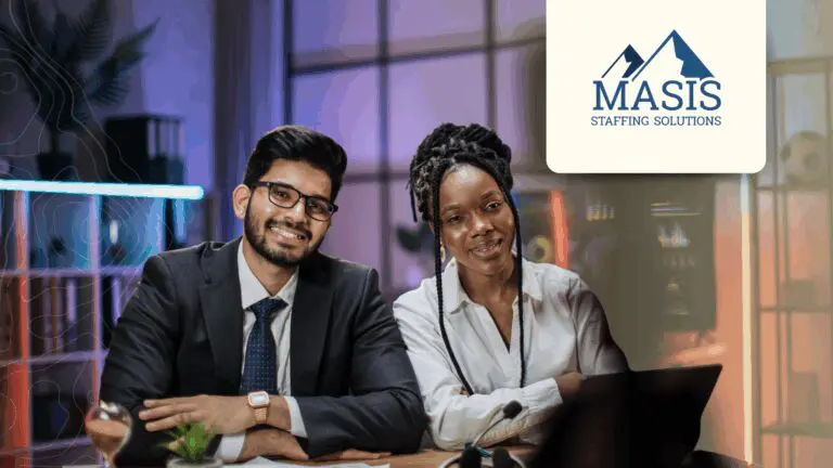 Two employees sit smiling at a desk
