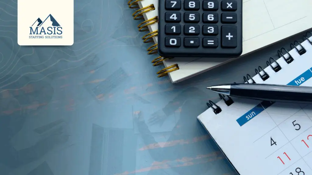 A flatlay of a desk with a calculator, pen, notebook, and calendar used for budgeting temp staffing