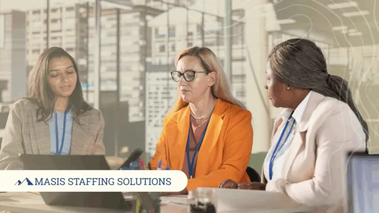 Three administrative role professionals discuss work at an office table