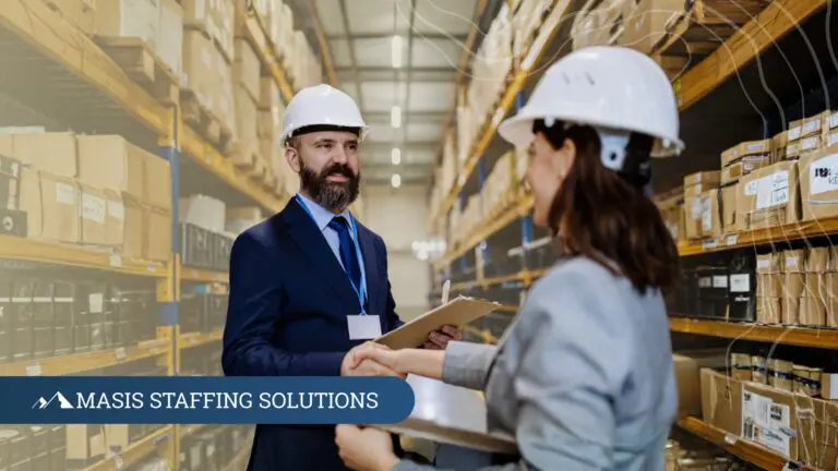 A logistics professional wearing a hard hat welcomes a new hire