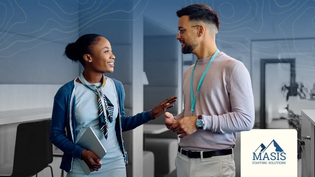 Two professionals stand in an office talking, illustrating active listening that drives retention.