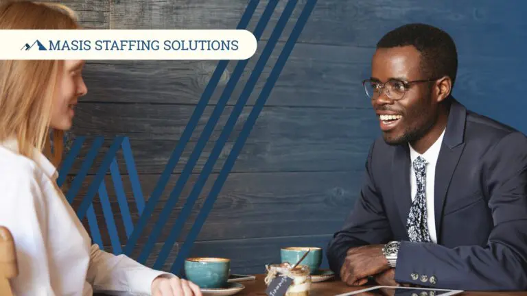 Two professionals in corporate attire talk animatedly over coffee.