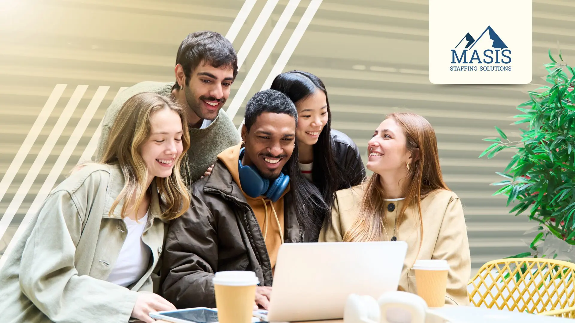 A group of Gen Z fresh graduates gather around a laptop