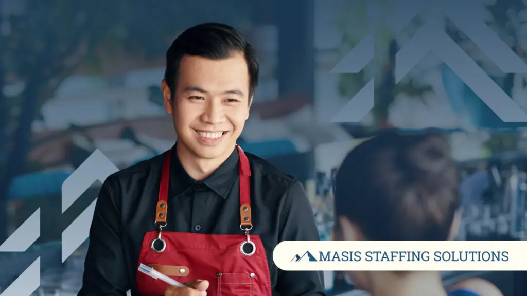 A hospitality professional smiles brightly at a guest.
