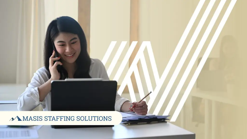 A recruiter makes a call while looking at a mobile tablet and holding a pencil in one hand, symbolizing recruiter roles moving from transactional to transformational.