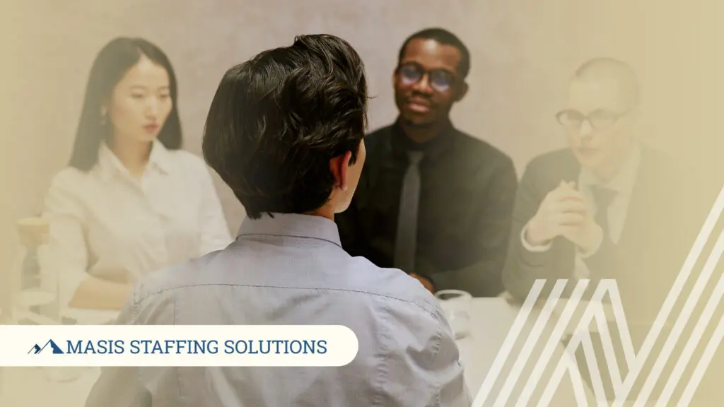 A candidate sits across from two interviewers at a table, representing the interview process and the feedback opportunity that follows every interview.