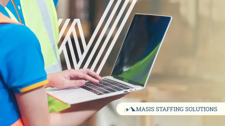 A worker in a safety vest types on a laptop, representing a temp worker taking initiative to pursue a permanent role.