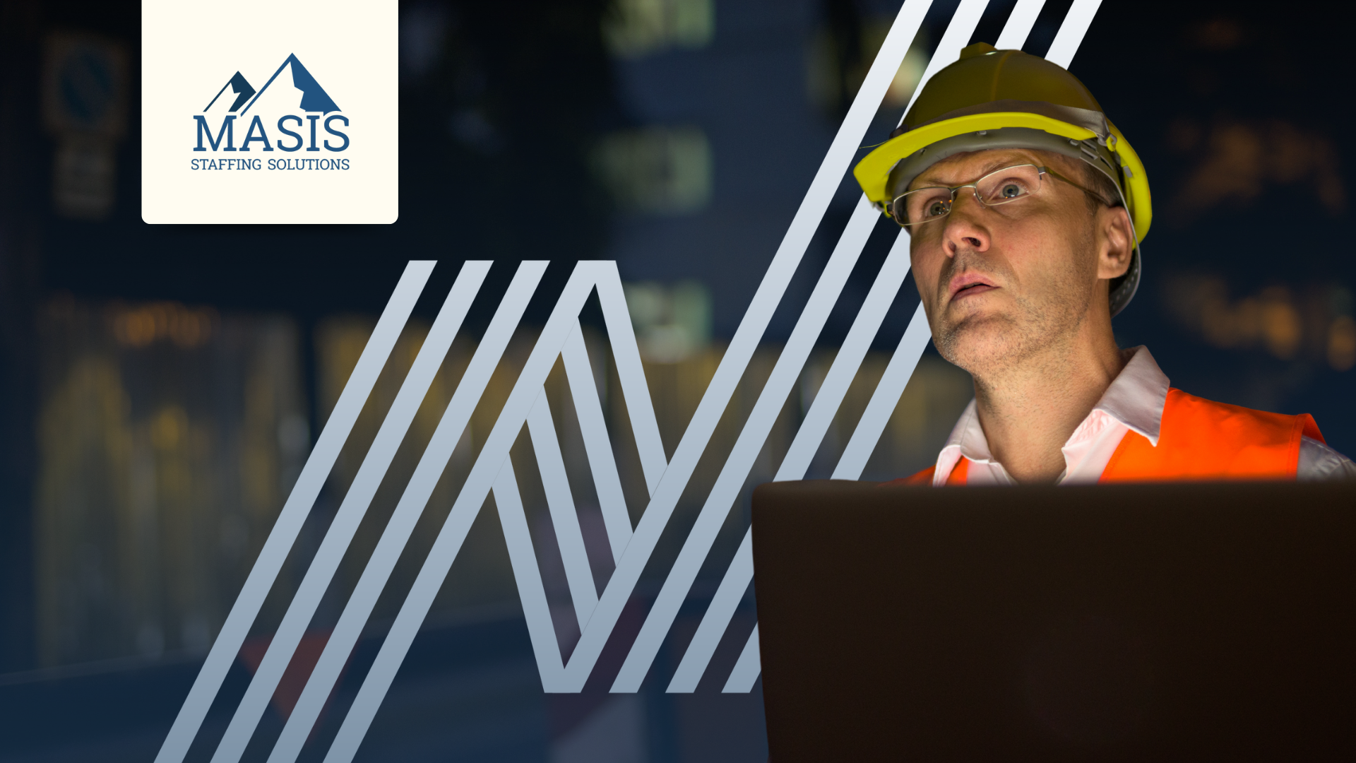 Light industrial staff wearing a hard hat, safety vest, and glasses stands in front of a screen, monitoring equipment