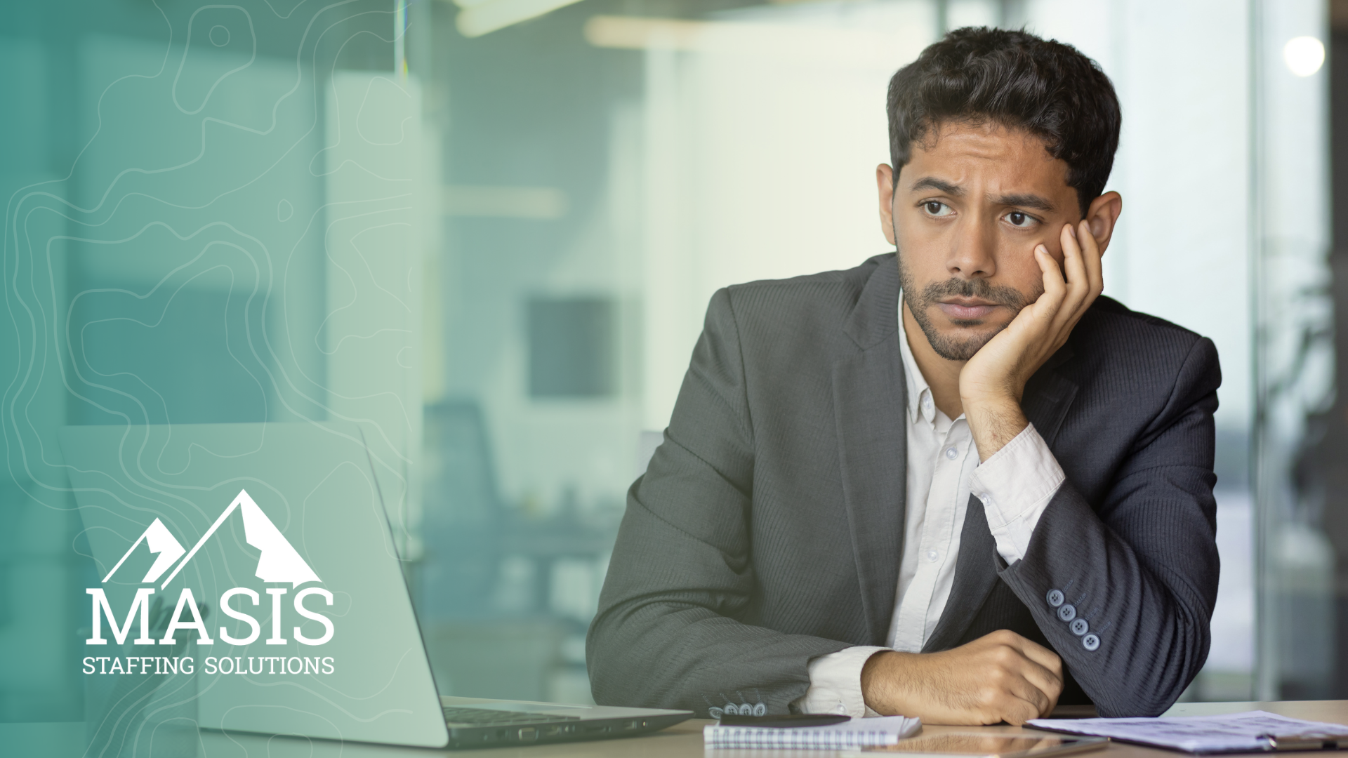 Employee sits at his desk with chin in hand, considering joining the summer resignation boom