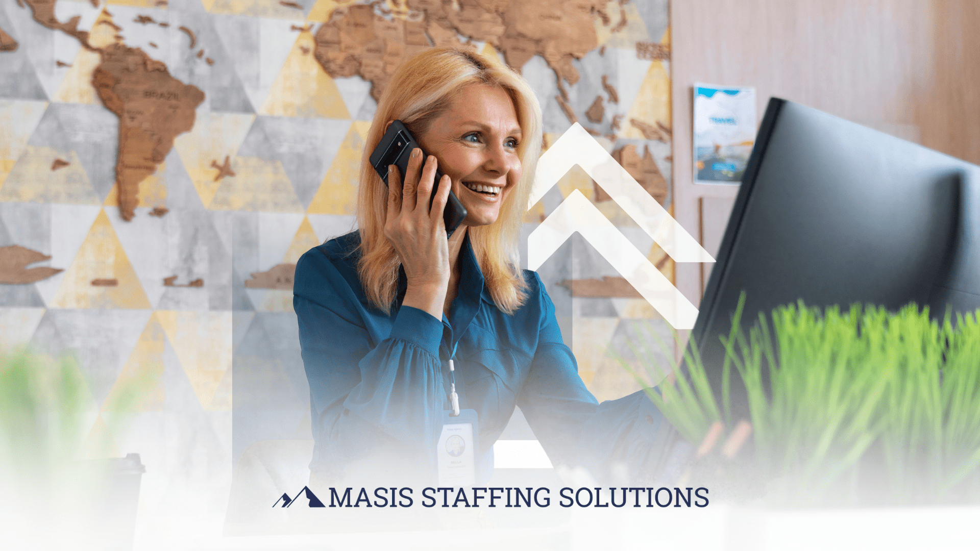 Call center employee speaks on a mobile device brightly while looking at a monitor screen