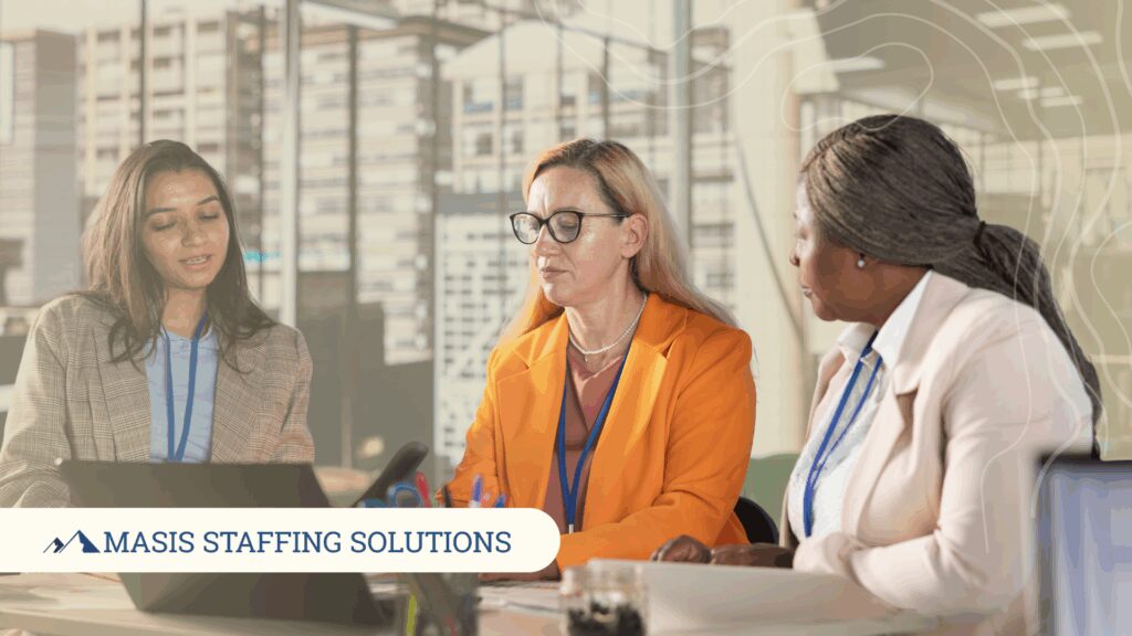 Three administrative role professionals discuss work at an office table